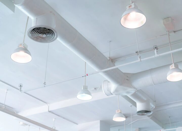 Industrial ceiling with exposed ducts and pendant lights.