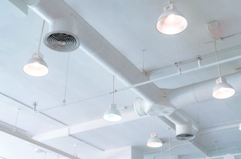 Industrial ceiling with exposed ducts and pendant lights.