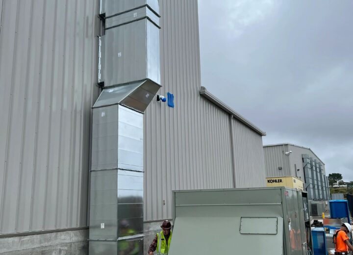 Large outdoor HVAC units and ductwork are installed beside a building.