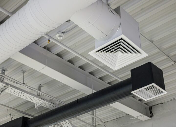 Close-up of industrial-style ventilation ducts and grilles on a ceiling.